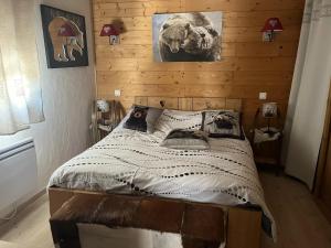 a bedroom with a bed with a wooden wall at Appartement spacieux à L'Argentière-la-Bessée, terrasse et jardin in LʼArgentière-la-Bessée