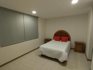 a bedroom with a bed with red pillows on it at Casa vacacional, en pueblo mágico Cholula in Cholula
