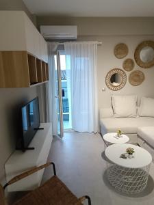 a living room with a white couch and a tv at Ioana Apartment Siviri in Siviri
