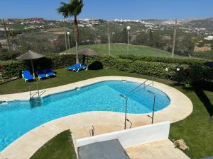 una piscina con dos sillas y una palmera en Lotus Golf, en San Luis de Sabinillas