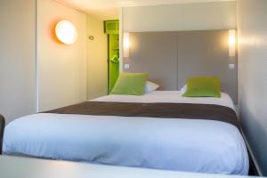 um quarto com 2 camas e almofadas verdes em Hotel inn Design Laval em Laval