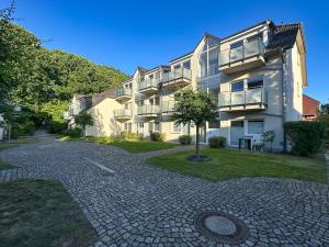 a large apartment building with a cobblestone driveway at Ferienanlage Eldena Ferienwohnung 12 in Lobbe
