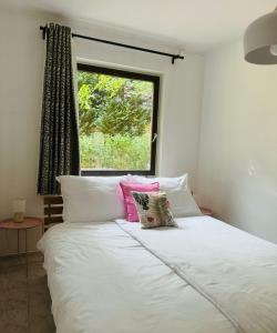 a bedroom with a bed with white sheets and pink pillows at SWEET Apartman in Miskolctapolca +18 photos