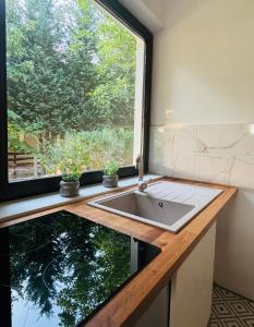 a kitchen with a sink and a window at SWEET Apartman in Miskolctapolca