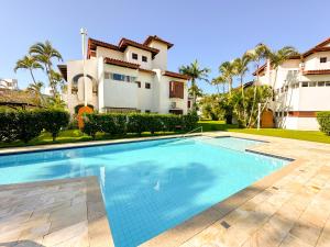 a swimming pool in front of a house at Apto estilo casa em condomínio com piscina na beira da praia in Florianópolis