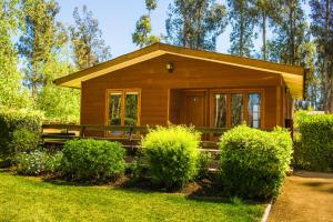 una pequeña casa de madera en un patio con arbustos en Parque San Juan - Héroes Parques, en San Antonio