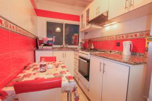 une cuisine avec des murs rouges, des armoires blanches et une table dans l'établissement شقة في وسط المدينة هادئة ومناسبة للعائلات, à Charf 8 autres photos