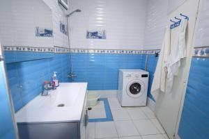 une salle de bains bleue et blanche avec un lave-linge. dans l'établissement شقة في وسط المدينة هادئة ومناسبة للعائلات, à Charf