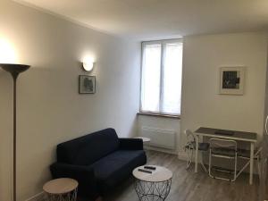 a living room with a blue couch and a table at Appartement climatisé Barjac centre ville in Barjac