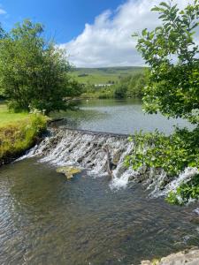 a river with a waterfall next to a body of water at Spacious Town House in Aberdare