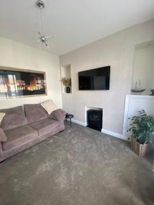 a living room with a couch and a flat screen tv at Spacious Town House in Aberdare