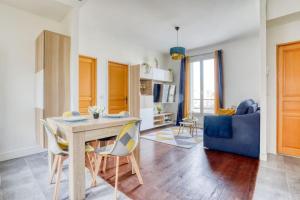 a living room with a table and a blue couch at Superbe T3 très proche Gare Sartrouville in Sartrouville