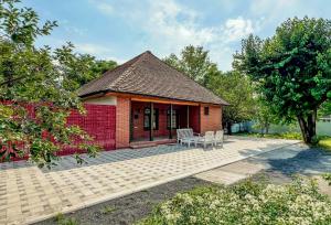 ein rotes Backsteinhaus mit zwei Stühlen und einer Terrasse in der Unterkunft Qafqaz Resort Greenway in Qəbələ
