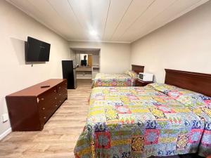 Una habitación de hotel con dos camas y un televisor de pantalla plana. en Budget Inn, en Jasper