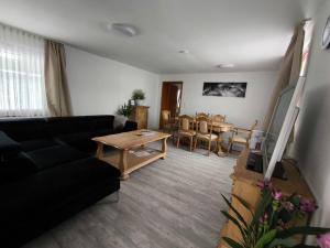 a living room with a black couch and a table at FeWo Antweiler Oberdorf in Mechernich