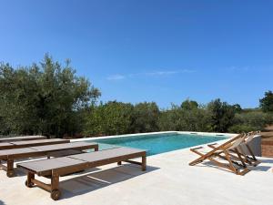 a swimming pool with wooden benches and a picnic table at Trulli Biancopumo - private pool in Monopoli