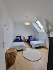 Un dormitorio abuhardillado con dos camas y una ventana. en PHARE DE LUMIÈRE DE ST-LUNAIRE spacieux, à 5 min de la plage, en Saint-Lunaire