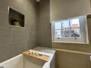 a bathroom with a bath tub and a window at Brand New Flat in Central London in London +23 photos