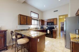 a large kitchen with wooden cabinets and a refrigerator at Leo’s Pool & Park House in Gilbert