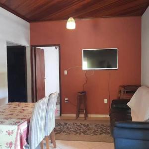 a living room with a table and a tv on a wall at Casa Paiol Grande in São Bento do Sapucaí