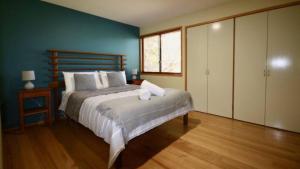 Un dormitorio con una cama grande y una pared azul. en Waterfront Hideway - Sanctuary Point - The Ultimate Spot to Relax, en Sanctuary Point