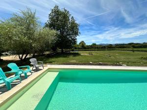 a swimming pool with two chairs and a table at Liberty sur Moment-Ardèche-com in Lablachère