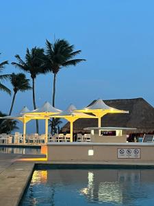 a resort with tables and umbrellas and a swimming pool at Spacious and comfortable apartment w pool and golf in Tulum