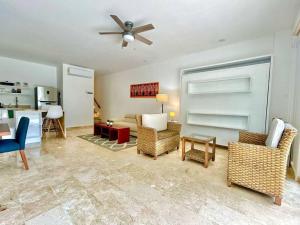 a living room with chairs and a ceiling fan at Spacious and comfortable apartment w pool and golf in Tulum