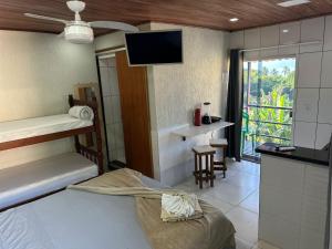 a room with a bed and a kitchen with a tv at Paraíso das Flores in Abraão
