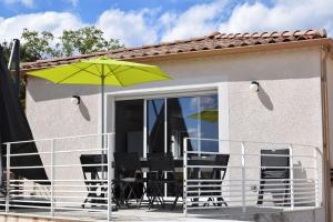 a patio with chairs and a green umbrella at Harmonia sur Moment-Ardeche-com in Rosières