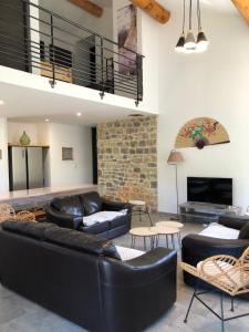a living room with black leather furniture and a stone fireplace at Kinsman sur Moment-Ardèche-com in Les Vans