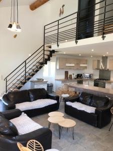 a living room with black leather furniture and a staircase at Kinsman sur Moment-Ardèche-com in Les Vans