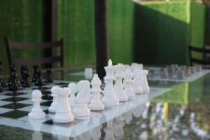 a chess board with white chess pieces on a glass table at casa com bela vista em Bragança Paulista in Bragança Paulista