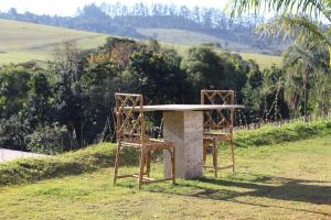 two chairs sitting next to a table in the grass at casa com bela vista em Bragança Paulista in Bragança Paulista