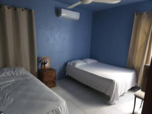 ein Schlafzimmer mit zwei Betten und einer blauen Wand in der Unterkunft Departamento en el corazón de cozumel in Cozumel + 2 Fotos