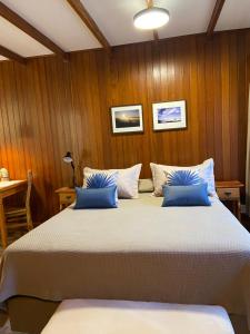 a bedroom with a large bed with blue pillows at Pousada OAK Plaza in Monte Verde