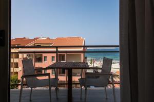 a table and chairs on a balcony with a view of the beach at Alma di Alghero Hotel in Alghero