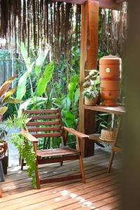 a wooden chair sitting on a porch with plants at Pousada Habitat Caraíva in Caraíva +36 photos