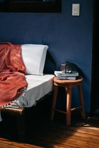 a bed with a table next to a blue wall at Pousada Habitat Caraíva in Caraíva
