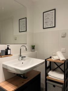 ein weißes Badezimmer mit Waschbecken und Spiegel in der Unterkunft Modernes Apartment mit Balkon und Parkplatz Zentrum in Hannover