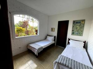 two beds in a room with a window at Recanto do Coração in Itaúna +40 photos