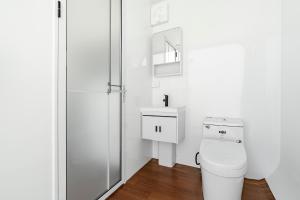 a white bathroom with a toilet and a sink at Field Tiny Home - Fruit & Sunset in Hall
