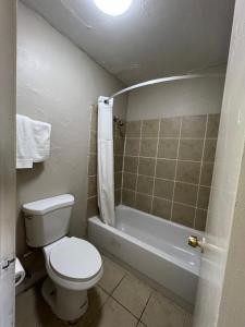 La petite salle de bains est pourvue de toilettes et d'une baignoire. dans l'établissement Great Western Inn & Suites, à Euless