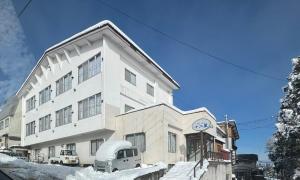 a building with a truck parked in front of it at Juniya Myoko in Myoko