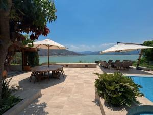 a patio with tables and umbrellas next to a pool at Casa el mirador-Valle de Bravo in Colorines