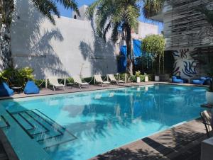 a large swimming pool with chairs and palm trees at The Double View Mansions Bali in Canggu