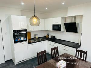 a kitchen with white cabinets and a sink and a table at Bachhaus am Rathaus 1 in Emden