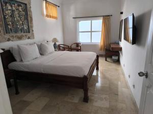 a bedroom with a bed with white sheets and a window at Hotel Sari Bunga in Legian