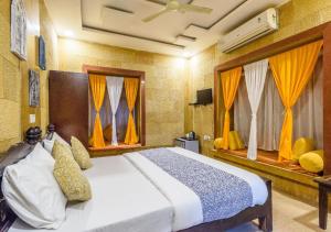 a bedroom with a large bed with yellow curtains at Hotel Meerana in Jaisalmer