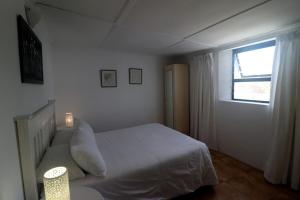 a bedroom with a white bed and a window at Dyers House Kassiesbaai Arniston in Arniston